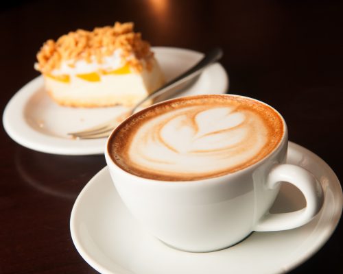 cappuccino cup with cake on the brown wooden table